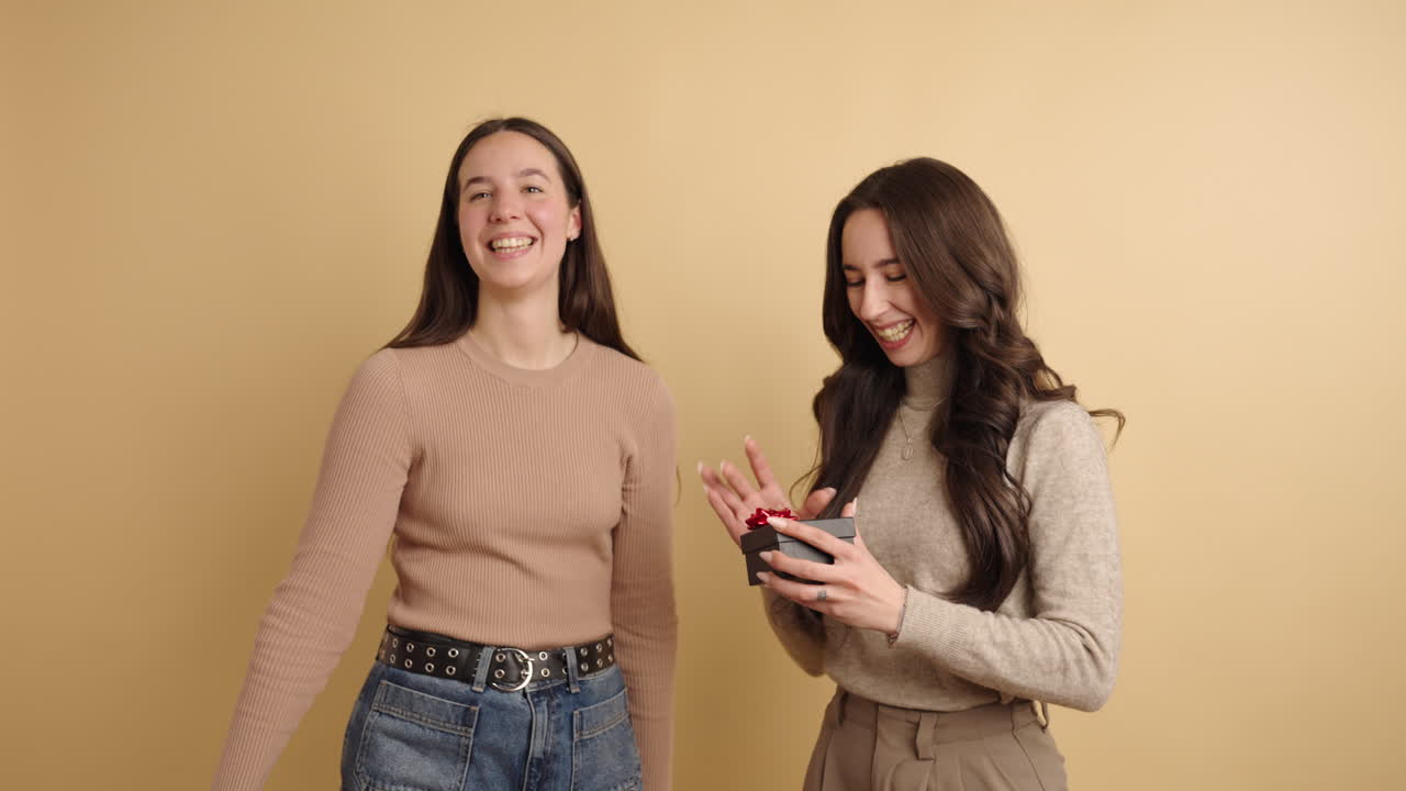 Young woman giving surprise gift to her friend