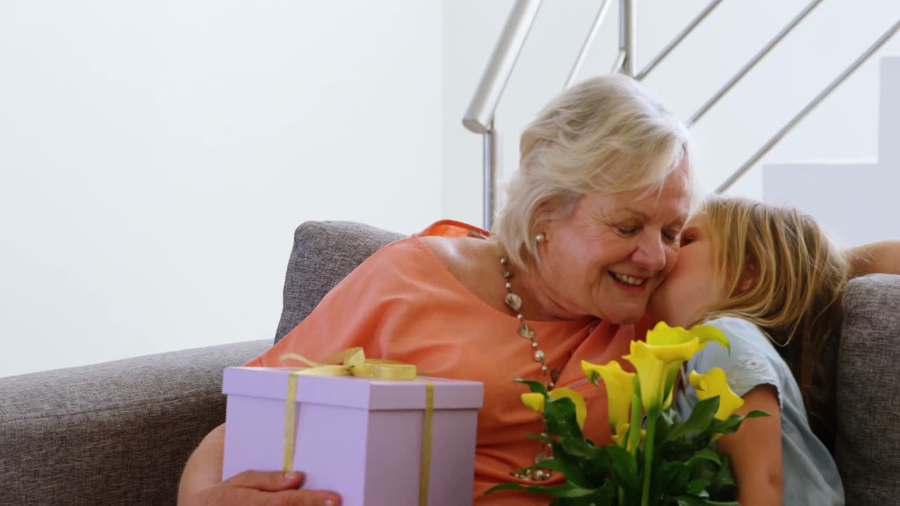 Enkelin küsst Großmutter im Wohnzimmer