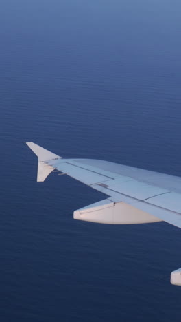 view from a plane window of the sky at sunrise with the wing of the plane in shot in vertical