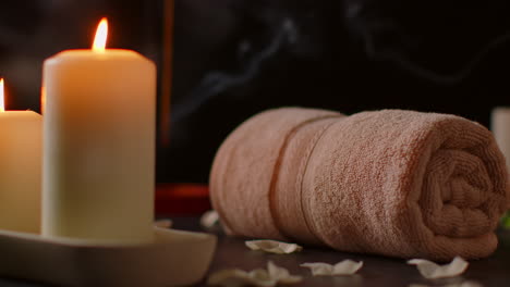 still life of lit candles with scattered petals incense stick and soft towels against dark background as part of relaxing spa day decor 1