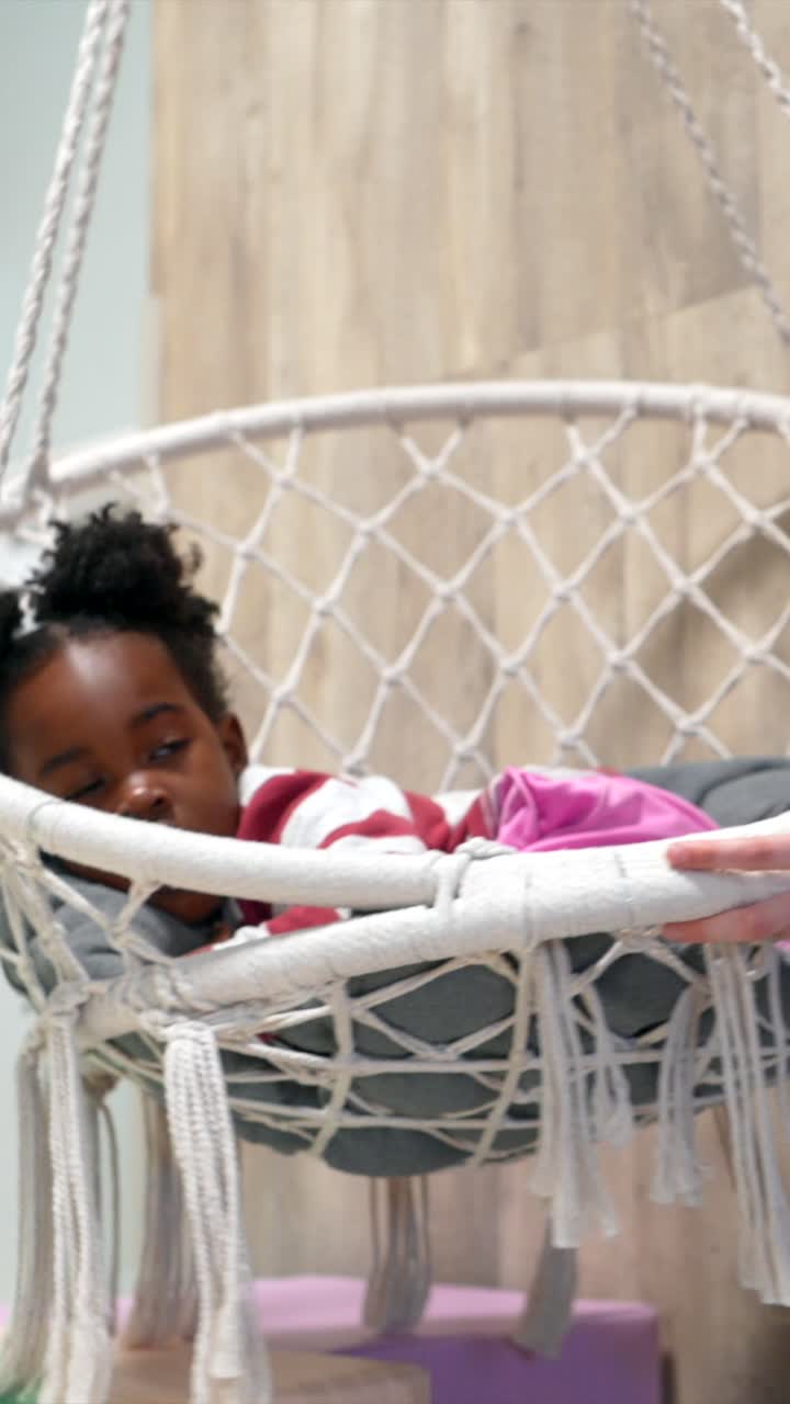 Woman Gently Swings Young Girl in a Hanging Macrame Chair