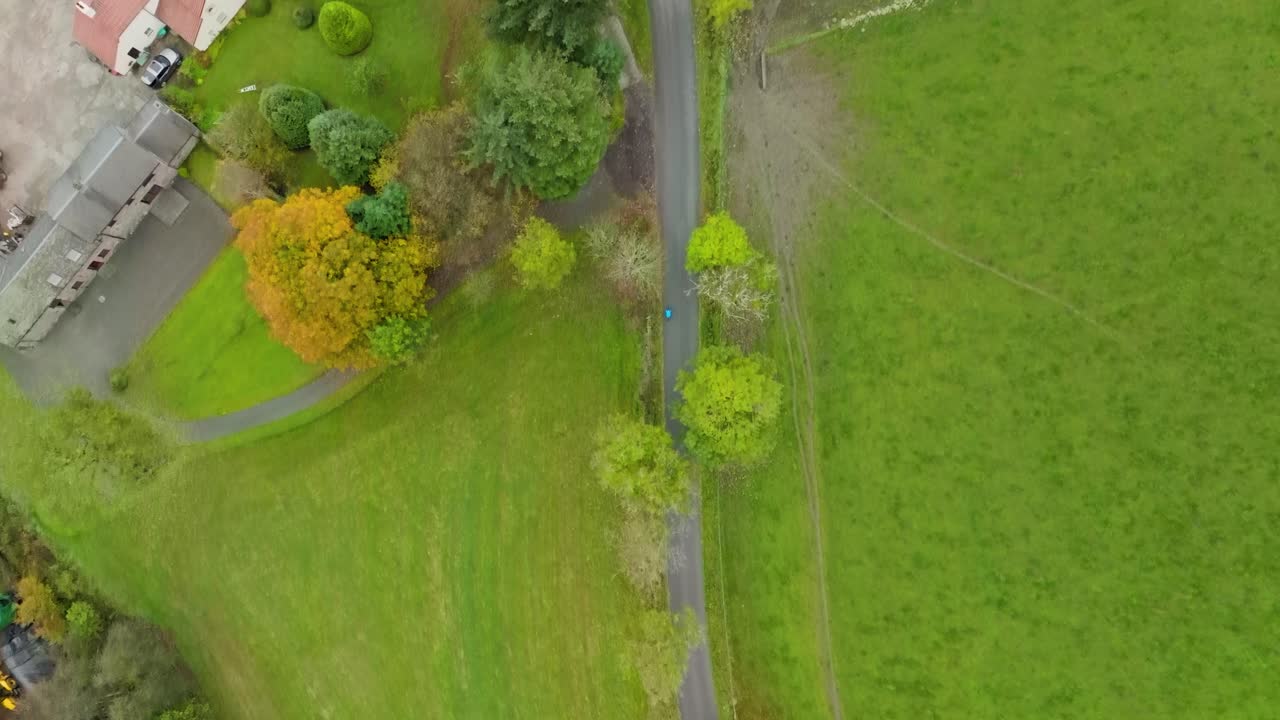 Cyclist on remote country lane, high aerial overhead shot of person riding bike