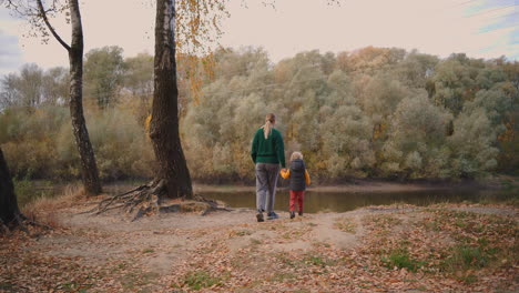 picturesque-landscape-of-autumn-nature-and-people-are-walking-in-forest-woman-with-baby-admiring-lake-and-colored-trees-resting-in-woodland-at-fall