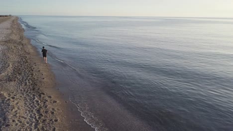 young runner man training on beautiful sunset at beach. drone view