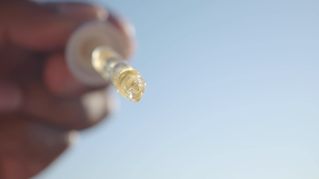 Hand holding a dropper bottle with liquid