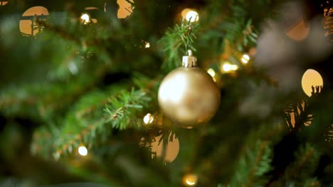 bola de navidad dorada y luces colgando de un árbol de navidad