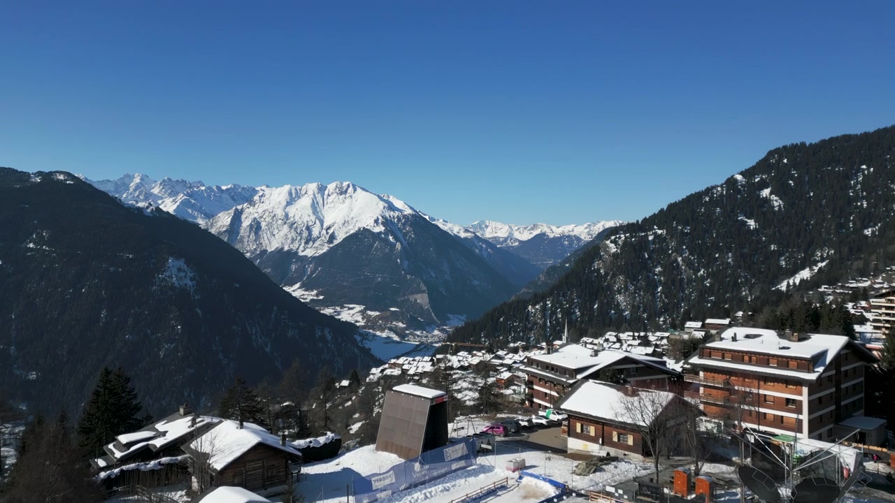 Vista aerea che si spinge verso la valle vicino a Verbier, Svizzera, con montagne e alberi in lontananza