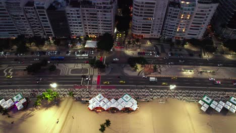 seguimiento filmado a lo largo de la playa de copacabana con el famoso diseño de la acera portuguesa por la noche, vista aérea