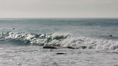 Ein-Surfer,-Der-Auf-Einer-Welle-Reitet,-Duckt-Sich-Aus-Einem-Shore-Break,-Als-Er-Einem-Felsen-Im-Wasser-Zu-Nahe-Kommt