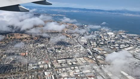 airplane flying above south san francisco, industrial city, california usa, plane passenger pov