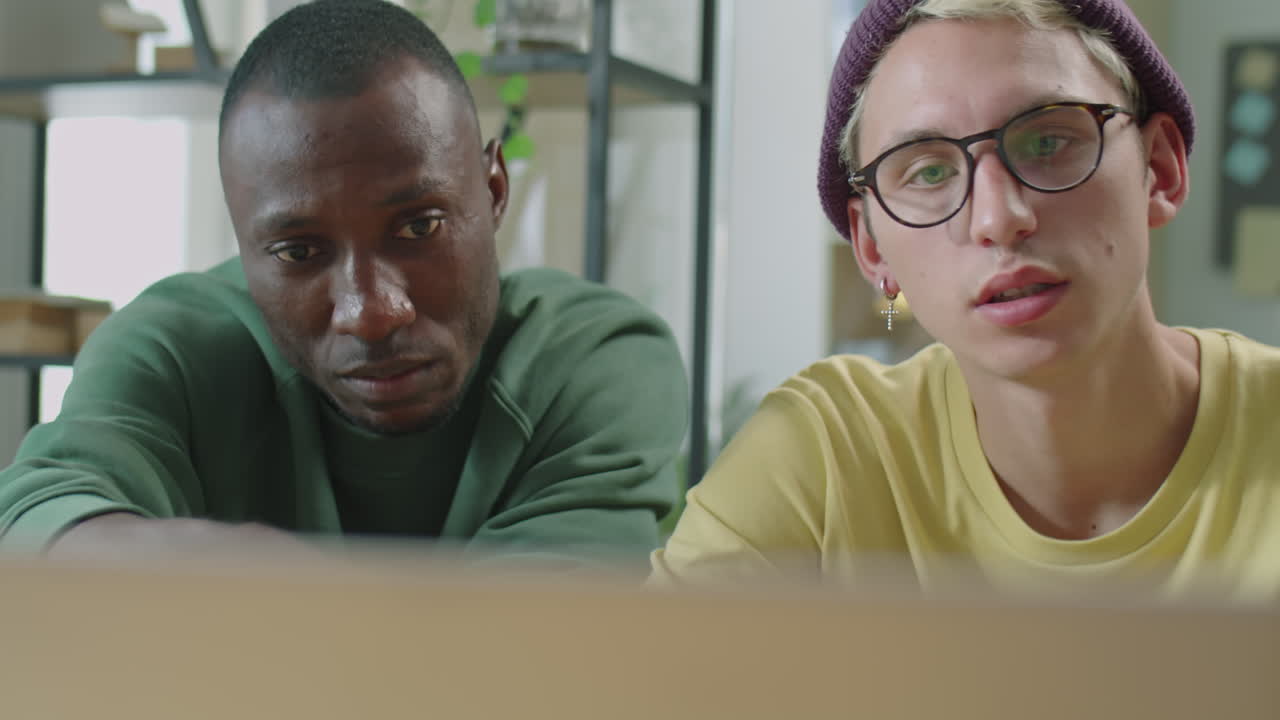 Diverse Gen Z Coworkers Using Laptop and Talking in Office