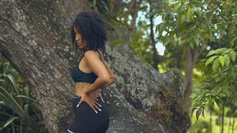 A-young-woman-stands-next-to-a-large-tree-trunk-before-turning-around-for-the-camera