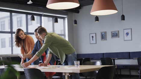 Diverse-male-and-female-colleagues-in-discussion-using-laptop-and-notes-in-casual-office-meeting