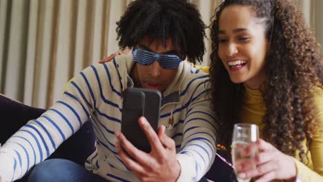 video de una feliz pareja diversa celebrando la víspera de año nuevo y haciendo una videollamada en el teléfono inteligente en casa