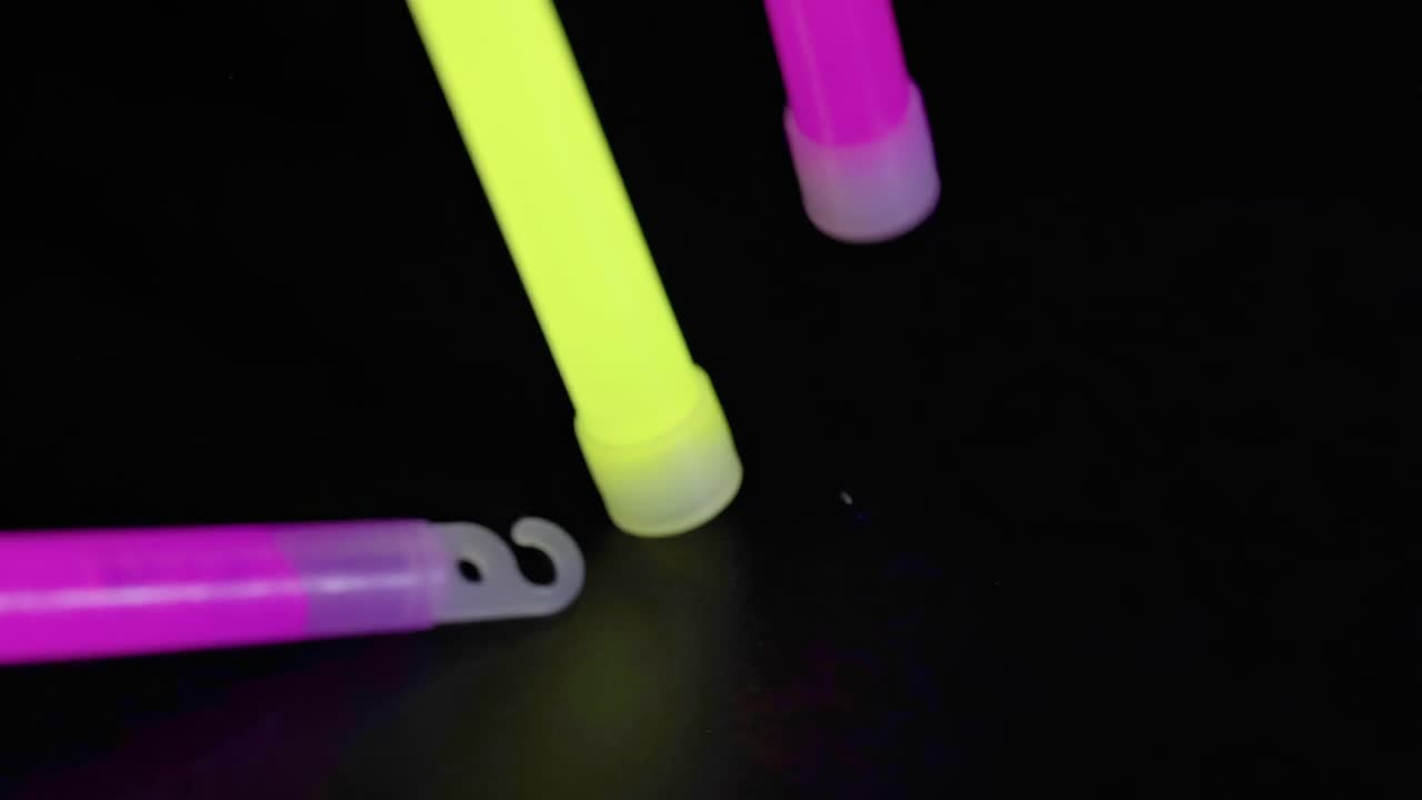 Colorful glow sticks arranged on a dark background, showcasing vibrant neon hues and captivating illumination.