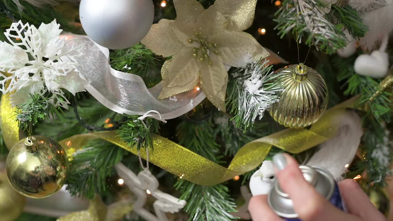 movimiento lento de decorar las ramas del árbol de navidad con spray de nieve falsa para navidad y año nuevo