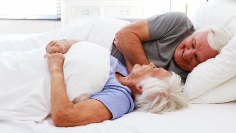 Happy-senior-couple-interacting-with-each-other-on-bed-