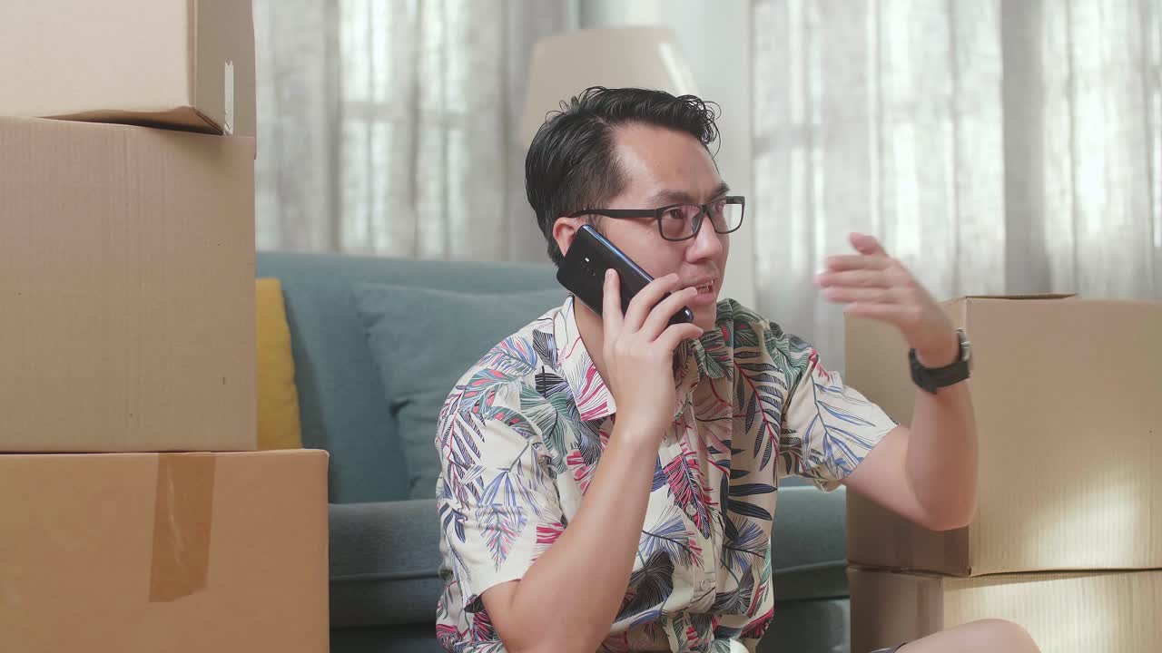 카드보드 상자 를 들고 바닥 에 앉아 새로운 집 으로 이사 한 후 스마트폰 에 대화 하는 아시아인 의 근접 사진