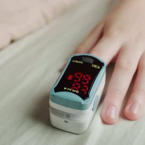 child's hand with a heart rate monitor on finger measures pulse and blood oxygen saturation