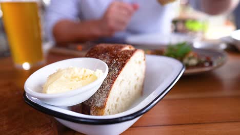 a person enjoys fresh bread and butter at a cozy cafe table, capturing a relaxed dining moment