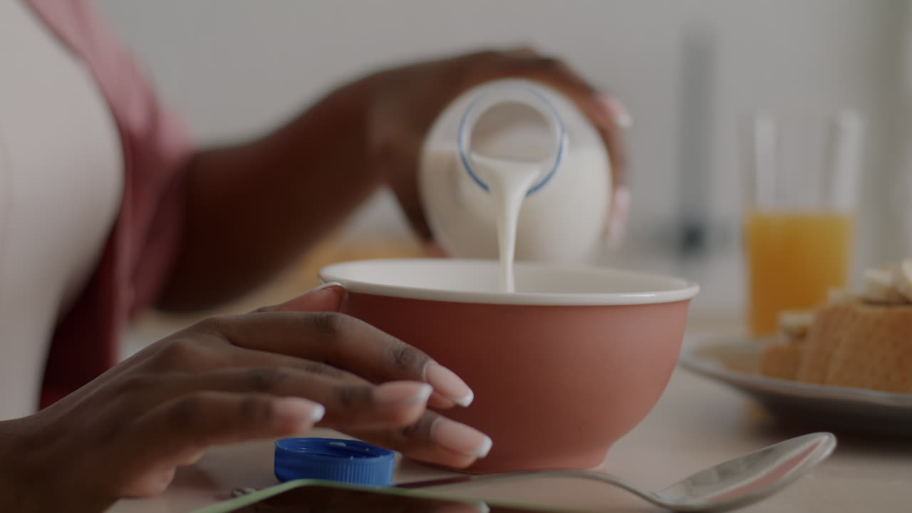 Woman pouring milk into bowl for breakfast