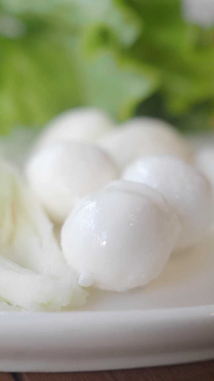 Close-up de bolinhos de peixe branco frescos e ingredientes em um prato.