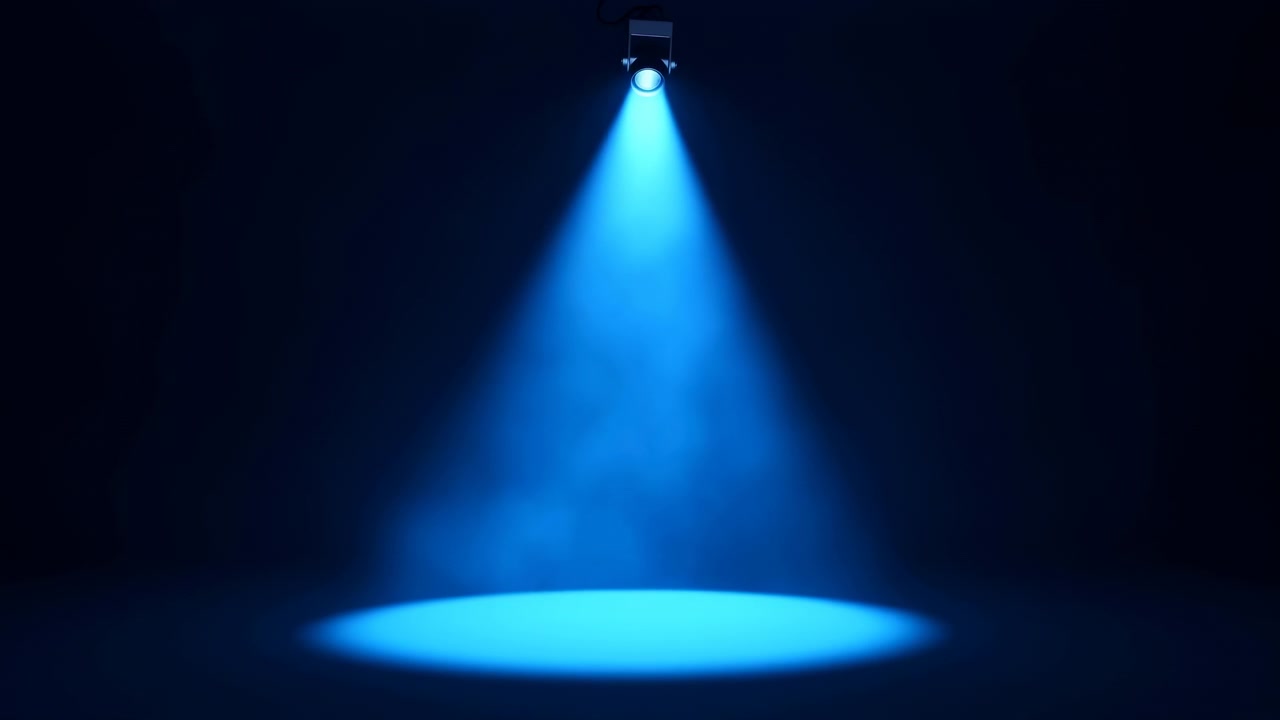 Una luce blu focalizzata brilla verso il basso attraverso la nebbia sopra una superficie scura, mentre l'area illuminata rimane centrata con sfumature morbide, ombre sottili e un'atmosfera cinematografica in un ambiente interno minimale.