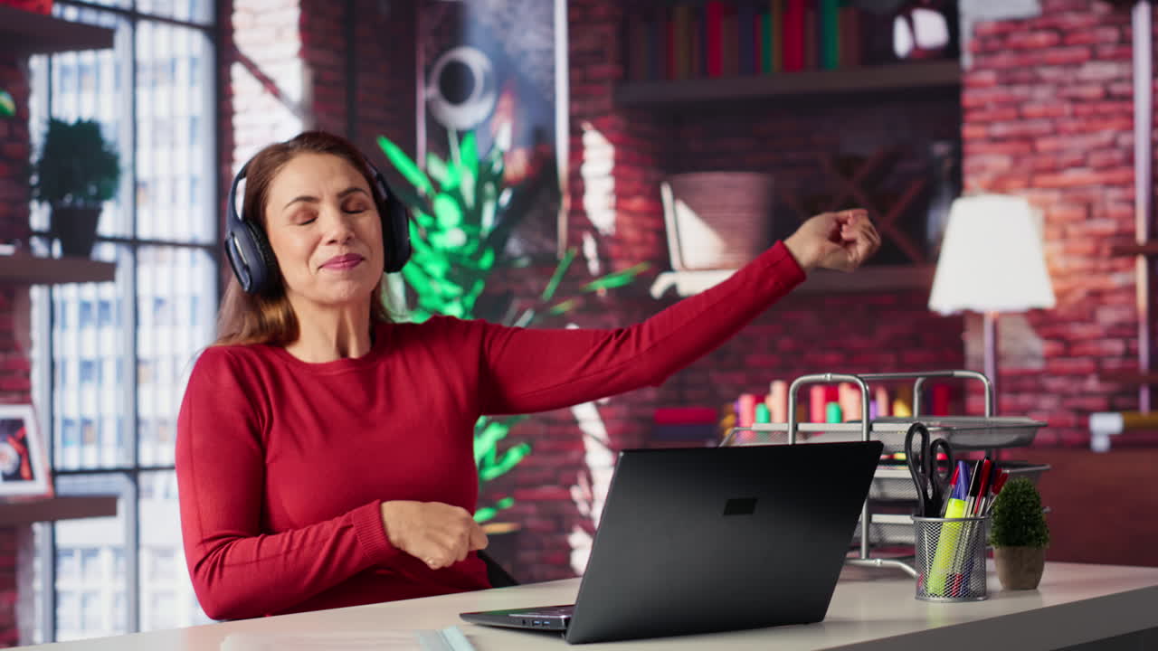 Woman working at desk with laptop and headphones