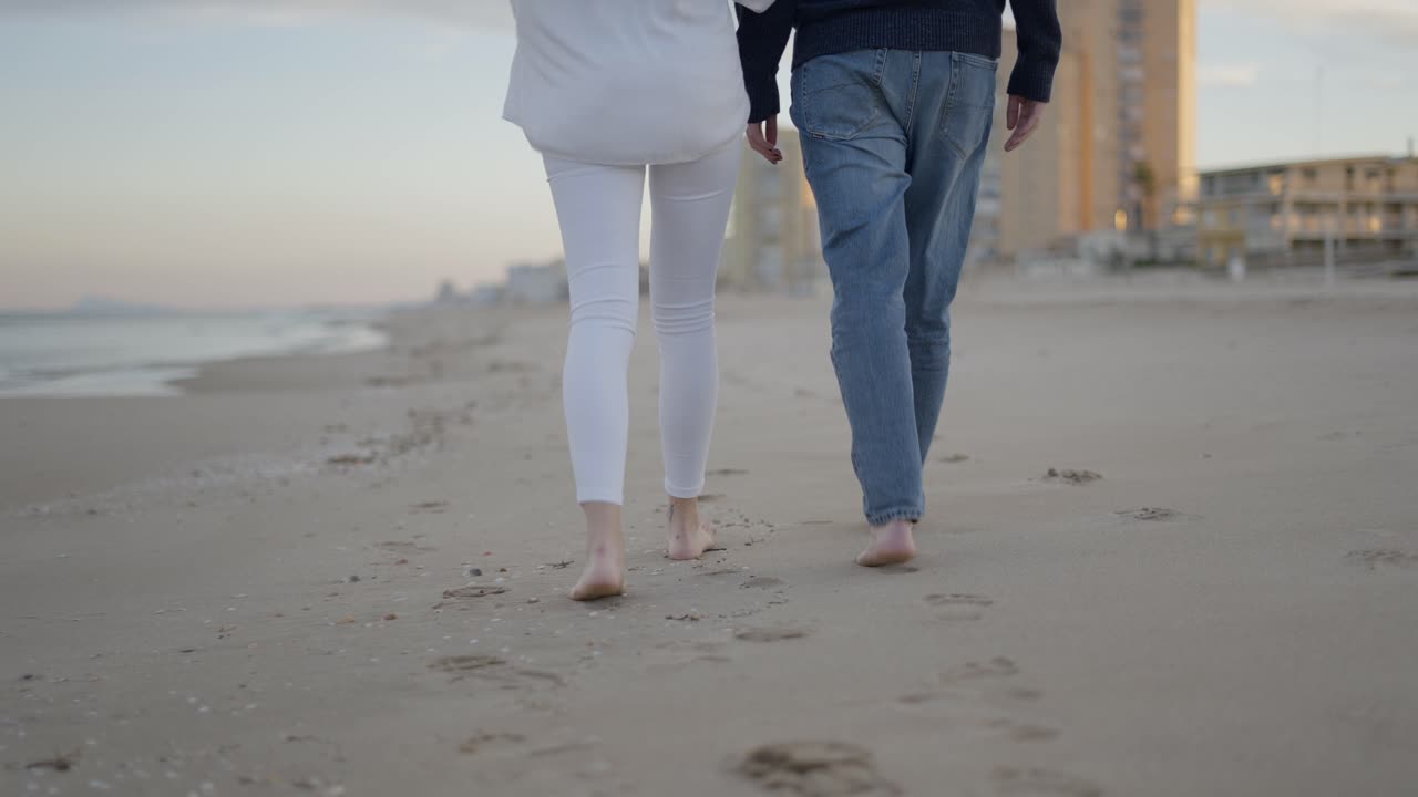 Couple Walking Barefoot on the Beach at Sunset