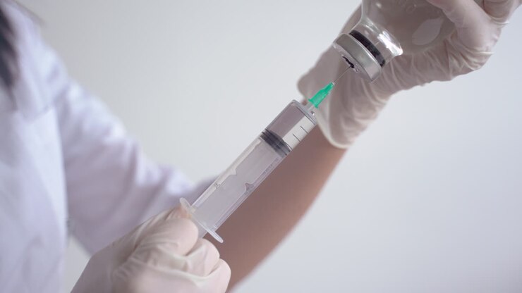 primer plano de las manos de un médico llenando una jeringa con una vacuna