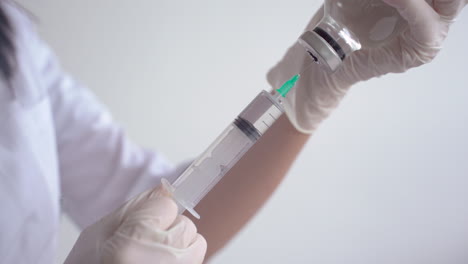 close up of hands of a doctor filling a syringe with a vaccine