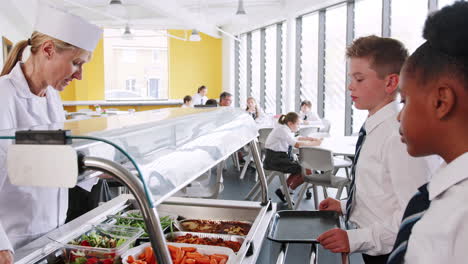 high school students wearing uniform being served food in canteen