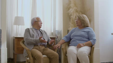 Mature-couple-sitting-in-chairs-and-talking-about-vaccination