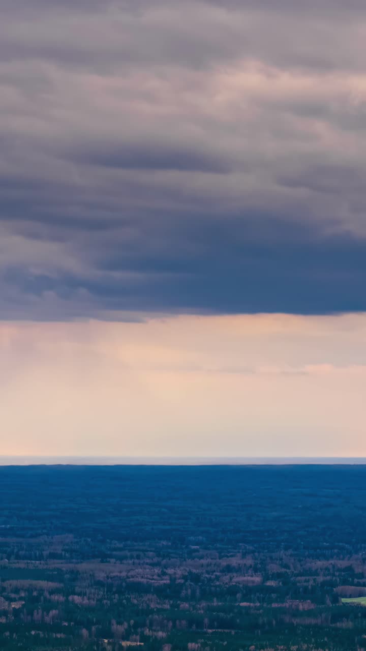 Clouds hover over vast landscape in moody vertical timelapse shot