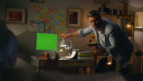 serious man pointing mockup pc at evening room closeup. guy eating sandwich