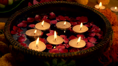 diwali decoration - woman keeping floating candles in a bowl / urli - diwali celebration