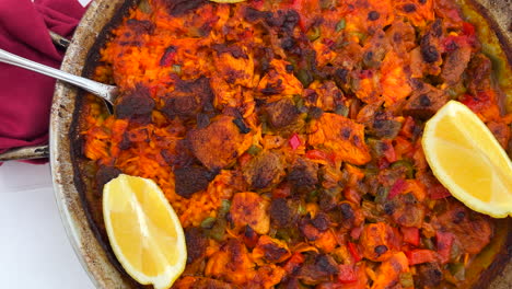 traditional spanish paella dish with chicken, vegetables and lemon slices in a restaurant, seafood with rice in marbella spain, 4k shot