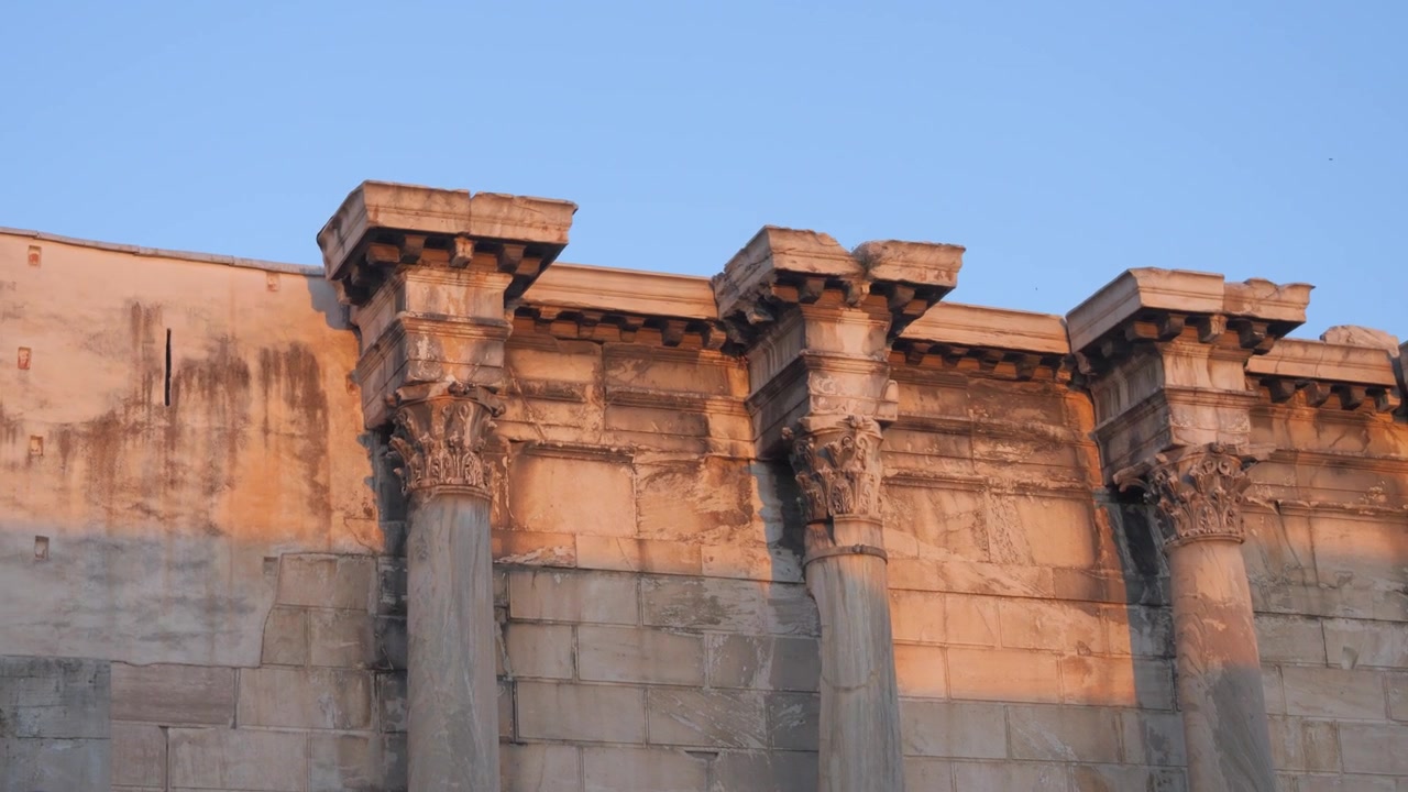 Colonne corinzie e muro di marmo che catturano la luce dorata presso la Biblioteca di Adriano ad Atene, Grecia.