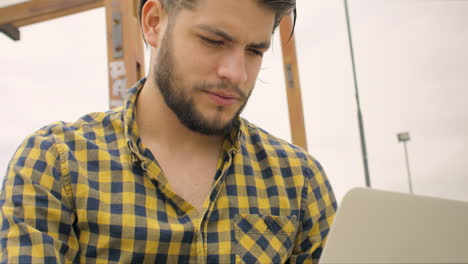 Hombre-Guapo-Sentado-En-Las-Escaleras-Usando-Una-Computadora-Portátil-Al-Aire-Libre