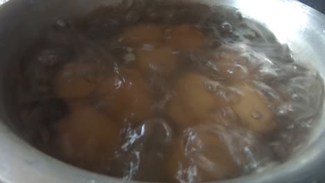 close up of eggs in boiling hot water in a pot pan in a kitchen