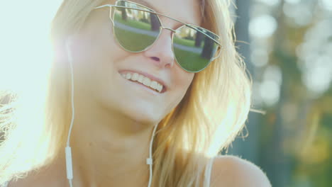 una mujer de aspecto modelo con gafas de sol escucha música al sol de vacaciones los rayos del sol