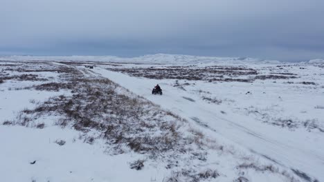 people on quad bike racing through winter landscape in iceland, adventure