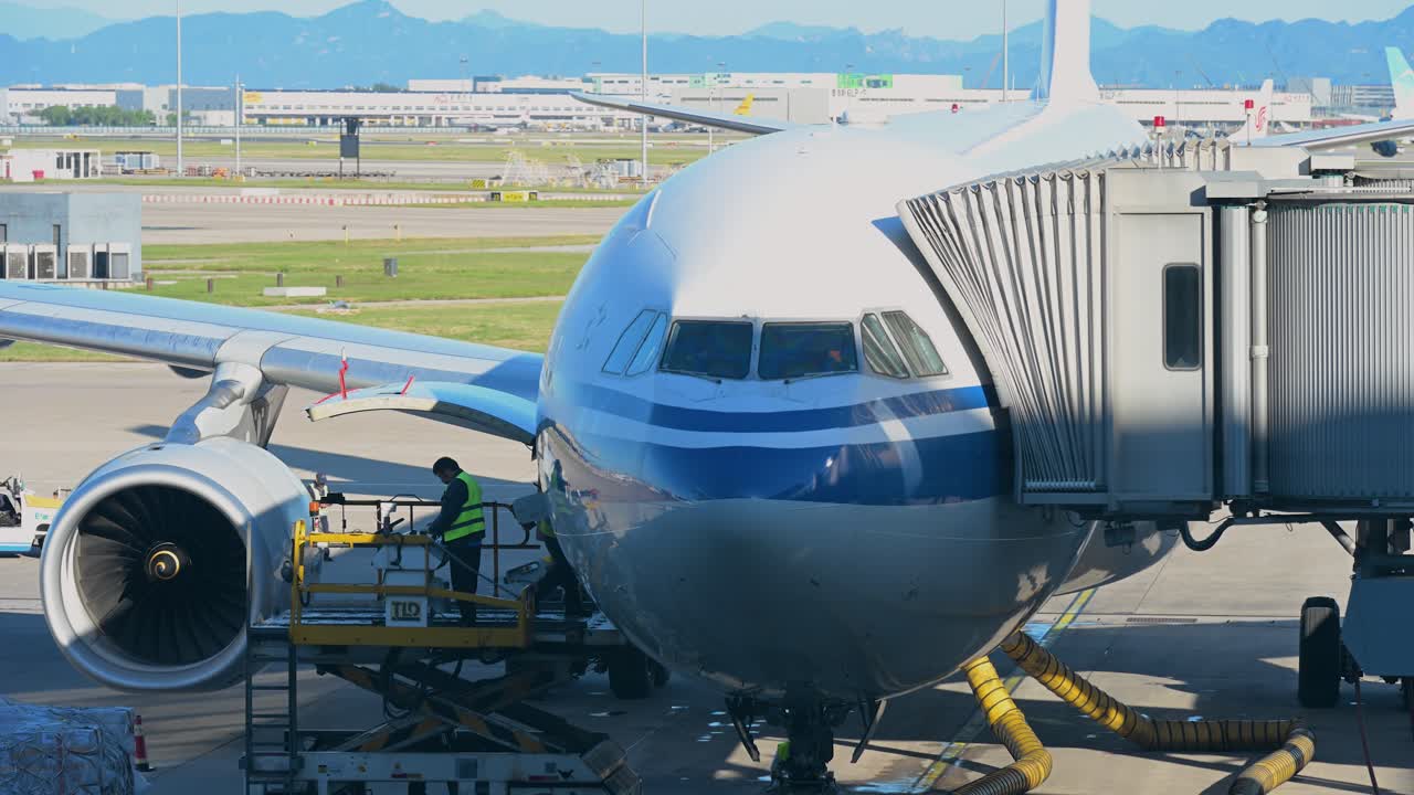 Workers are seen servicing a plane stationed on the runway at Beijing International Airport, China, prior to its departure.