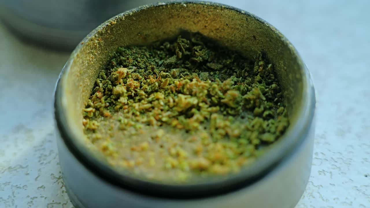 Macro view, ground cannabis plant inside grinder, herbal texture in close detail