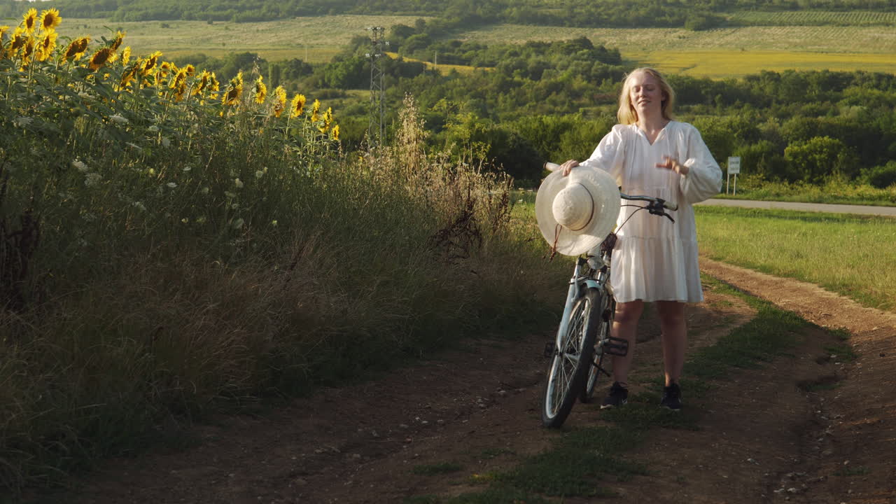 저녁 황금 시간 꽃 장면을 냉각하기 위해 pushbike와 함께 잠시 멈추는 소녀
