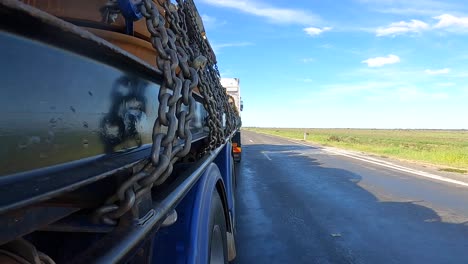 Recorded-shot-from-the-merchandise-area-of-a-truck,-landscape-with-low-vegetation-and-blue-sky-with-clouds-on-the-horizon