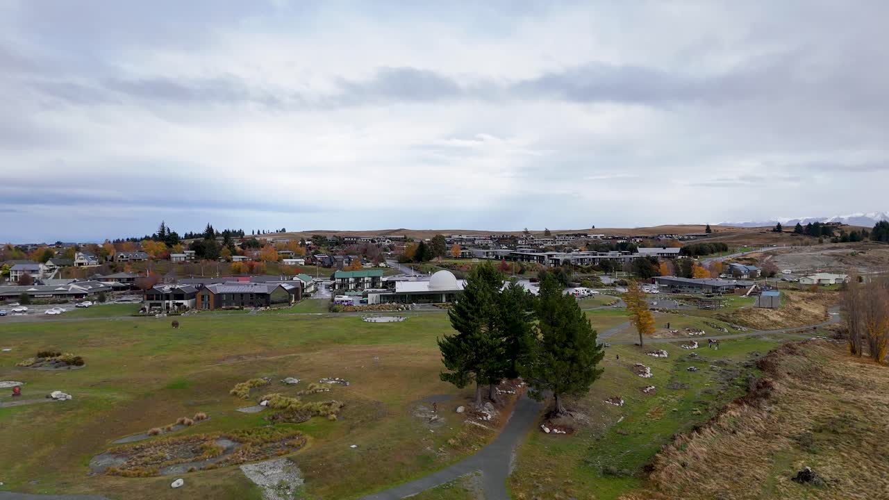 Aerial footage captures Lake Tekapo village under overcast skies, showcasing natural landscapes and residential areas with gentle camera movement