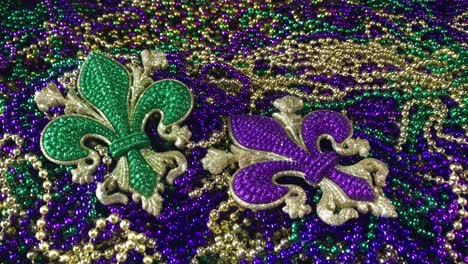 sparkling fleur de lis in green and purple on pile of beads