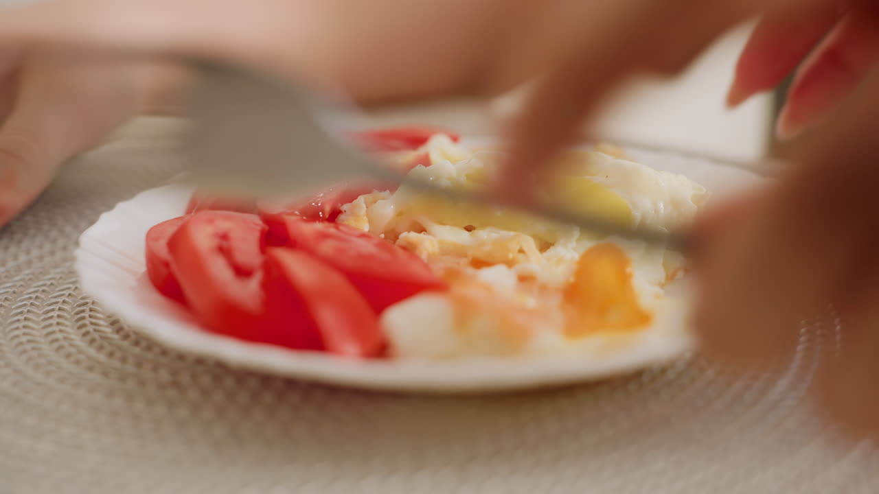 Close up of chef carrying plate with fried egg and sliced tomato to serve child seated at table, capturing warm homemade meal, family routine, healthy food preparation