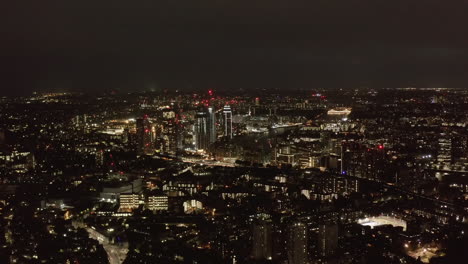 Vista-Panorámica-Aérea-De-La-Gran-Ciudad-Por-La-Noche.-Luces-De-La-Ciudad-Brillando-En-La-Oscuridad.-Volar-Por-Encima-Del-Barrio-Urbano.-Londres,-Reino-Unido